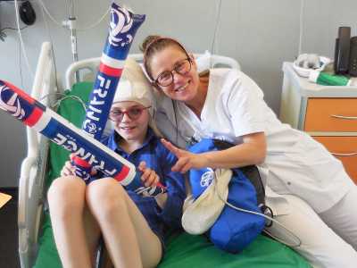 Photo de Caroline Jomard Serbin et d'une enfant souriante sur un lit d'hôpital durant un match de l'équipe de France de footbal